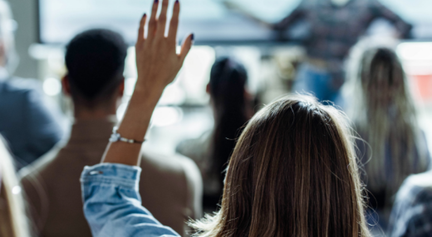 Back view image of a woman raising her hand in a presentation